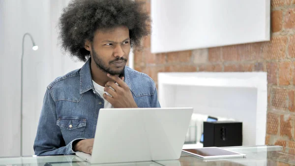 Tänkande afrikansk man arbetar på laptop — Stockfoto