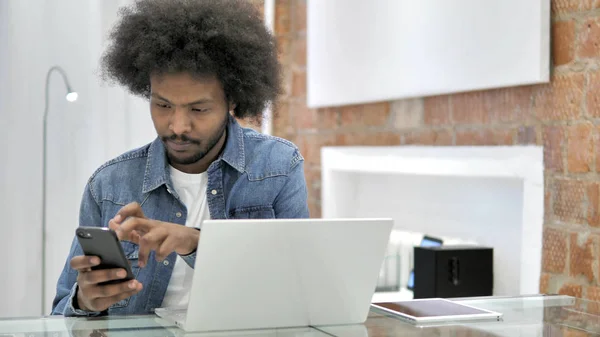 African Man za pomocą smartfona i laptopa — Zdjęcie stockowe