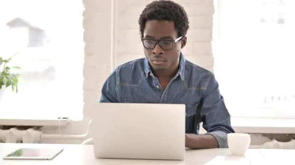 年轻的非洲男子在笔记本电脑上工作 — 图库照片