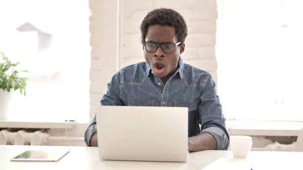 Шокований африканський чоловік Цікаво і працює на ноутбуці — стокове фото