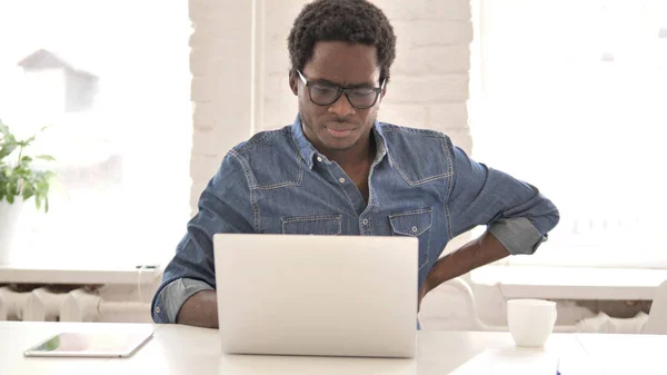 African Man with Back Pain working on Laptop