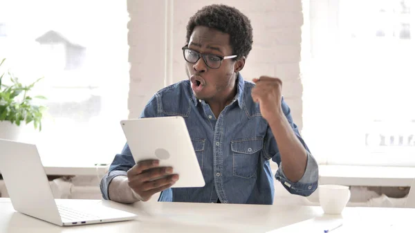 African Man Celebrating Success while Using Tablet