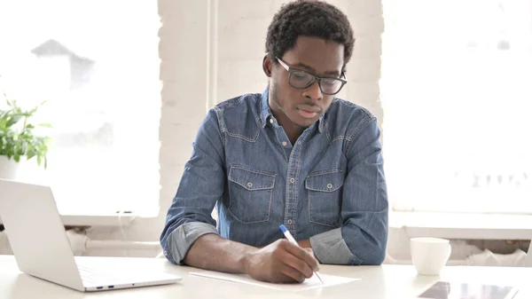 African Man Writing Letter at Work