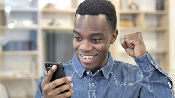 Emocionado joven africano feliz hombre usando Smartphone —  Fotos de Stock