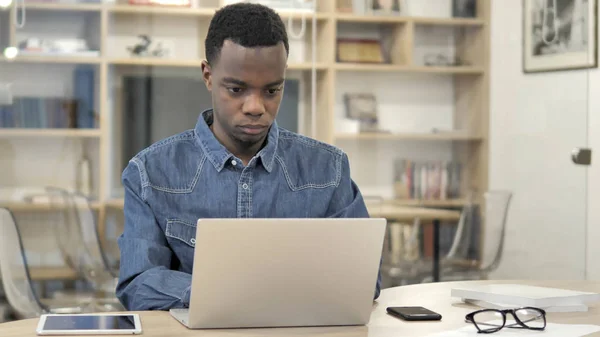 Ung afrikansk man som arbetar på laptop — Stockfoto