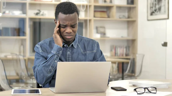 Bolest hlavy, unavený mladý Afričan práce na přenosném počítači — Stock fotografie