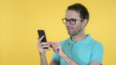 Genç Adam Sarı Arka Plan da İzole Smartphone Kullanırken Başarı Için Heyecanlı