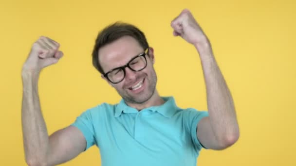 Счастливый молодой человек танцует на желтом фоне — стоковое видео