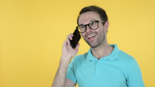 Jovem falando em Smartphone isolado em fundo amarelo — Vídeo de Stock