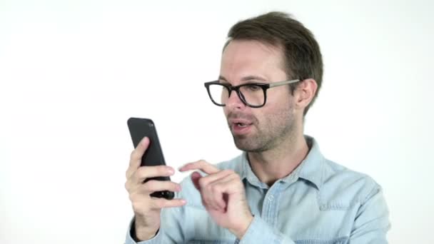 Νέος άνθρωπος ενθουσιασμένος για την επιτυχία, ενώ χρησιμοποιείτε smartphone απομονωμένη σε λευκό φόντο — Αρχείο Βίντεο