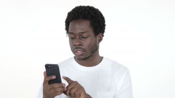 Jeune homme africain excité pour le succès tout en utilisant Smartphone isolé sur fond blanc — Video