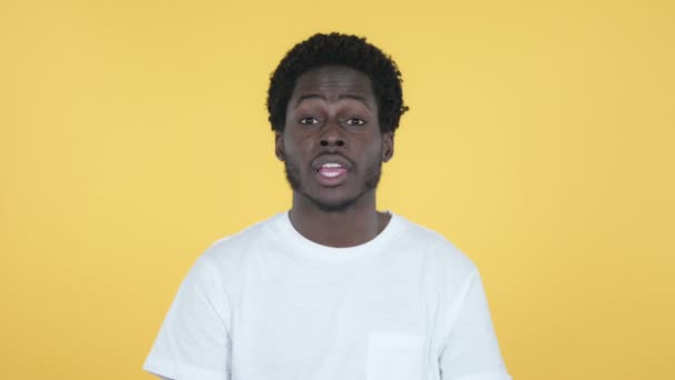 黄色の背景に分離カメラを指してアフリカ青年 — ストック動画