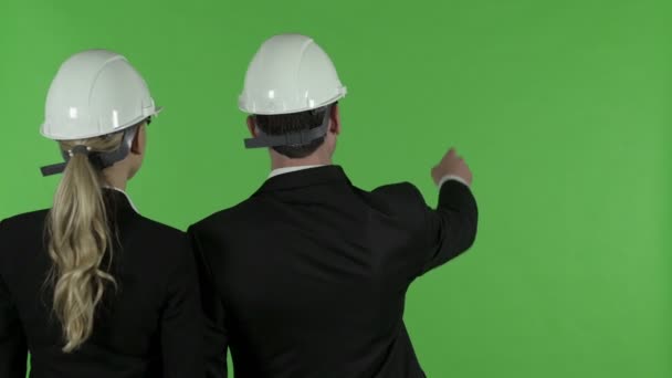 Zadní pohled na mužského inženýra ukazující nahoru na ženskou inženýra, klíč Chroma — Stock video
