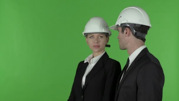 Vista lateral del ingeniero de construcción femenino señalando de pie con el ingeniero masculino, llave de croma — Vídeos de Stock
