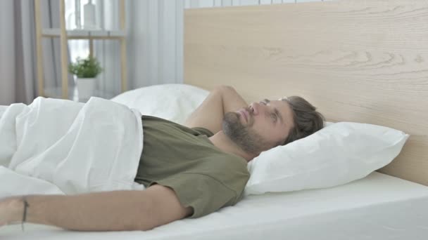 Hombre joven preocupado no puede dormir y mirar a su alrededor — Vídeos de Stock