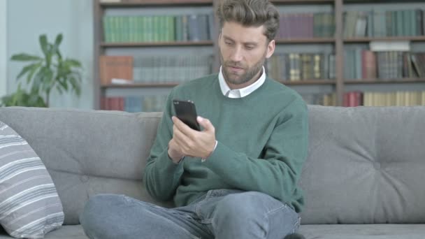 Unglücklicher junger Mann checkt sein Telefon und fühlt sich besiegt — Stockvideo
