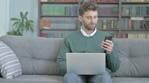 Hardworking Man pracy na laptopie podczas sprawdzania jego telefon — Wideo stockowe