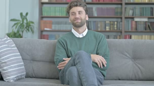 Šťastný mladý muž sedí na pohovce a kašle — Stock video