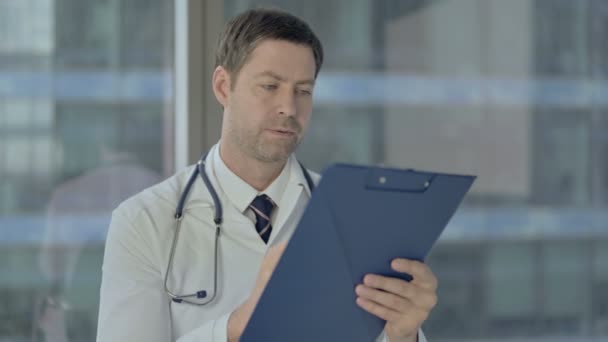 Серьезный врач изучает медицинские документы, бумажную работу — стоковое видео