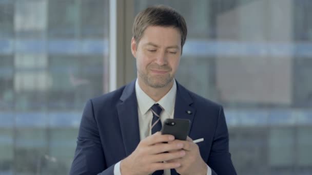 Zakenman scrolling smartphone op het werk — Stockvideo