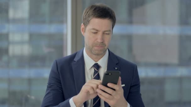 Geschockter Geschäftsmann benutzt Handy und regt sich auf — Stockvideo
