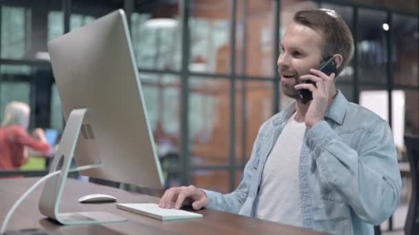 Mladý muž mluví po telefonu v práci — Stock video