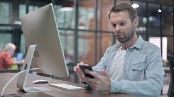 Junger Mann nutzt Smartphone bei der Arbeit — Stockvideo
