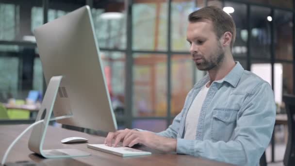 Jonge man die naar de camera kijkt terwijl hij aan het werk zit — Stockvideo