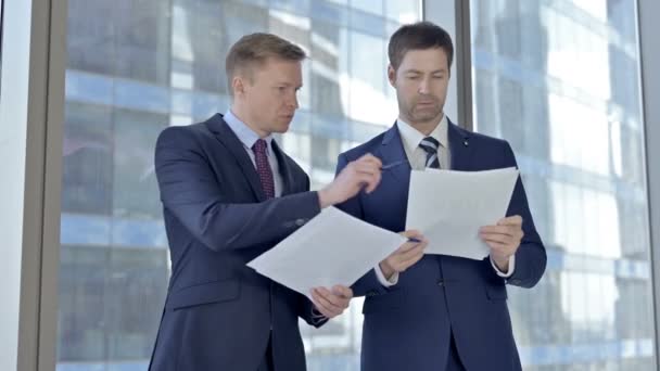 Два бизнесмена среднего возраста проверяют документы на наличие окна в офисе совета директоров — стоковое видео