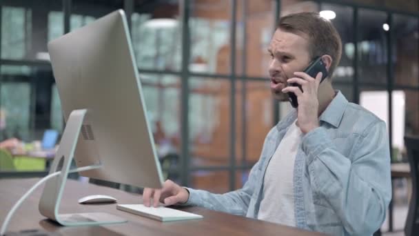 Joven enojado hablando por teléfono en el trabajo — Vídeos de Stock