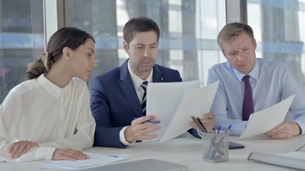 Uitvoerende zakenmensen delen informatie via documenten op kantoor tafel — Stockvideo