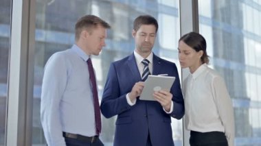 Orta Yaşlı İşadamı Ofiste Yardımcıları ile Tablet üzerinde Kaydırma