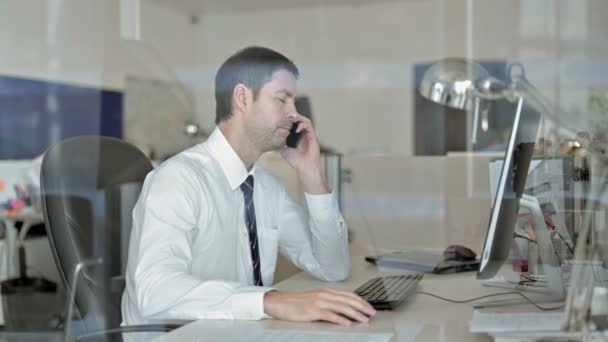 Ambiciózní obchodník středního věku mluví na svém mobilu v kanceláři — Stock video