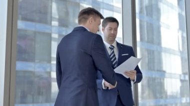 İki Orta Yaşlı İşadamı Belgeleri Tartışıyor ve Ofiste El Sıkışıyor