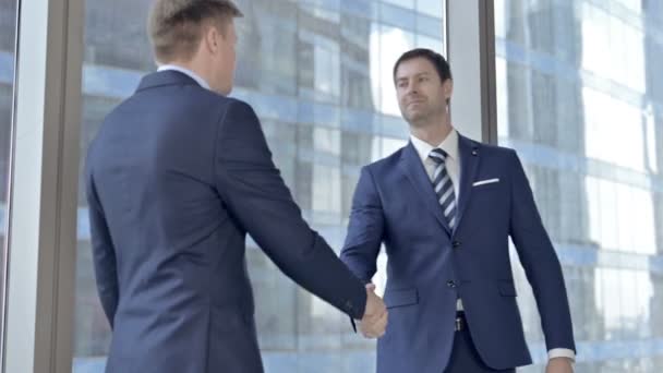 Расстроенные бизнесмены среднего возраста пожимают руку и передают деньги в окно офиса — стоковое видео