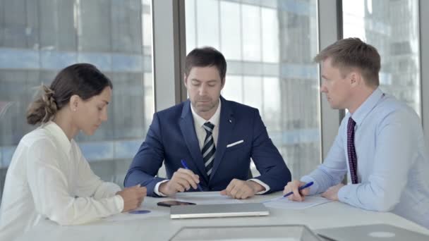 Empresario de mediana edad explicando cosas a sus asistentes en la mesa de juntas — Vídeo de stock