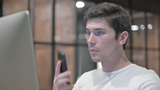 Mladý muž mluví po telefonu v práci — Stock video