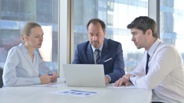 Orta Çağ İşadamı Dizüstü bilgisayar kullanıyor ve Ofis Masasındaki Yardımcılara Açıklıyor