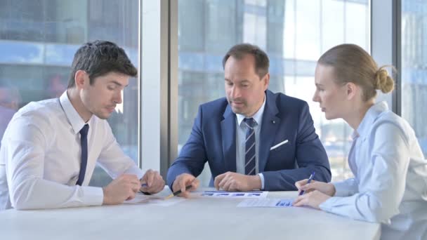 Medelålders affärsman som har föredrag om dokument med assistenter på Office Table — Stockvideo