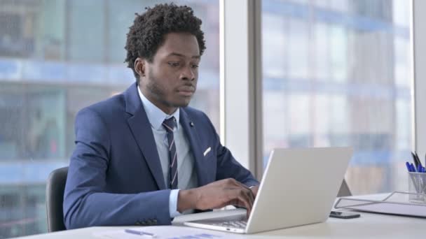 Uomo d'affari afroamericano Pensare e utilizzare il computer portatile in ufficio — Video Stock