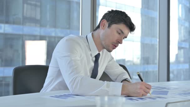 Jeune homme d'affaires travaillant sur des documents de projet sur bureau — Video