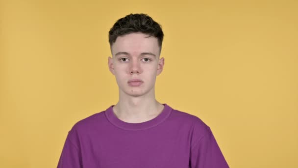 Junger Mann winkt zur Begrüßung auf gelbem Hintergrund — Stockvideo