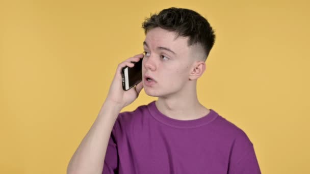 Junger Mann spricht auf Smartphone vor gelbem Hintergrund — Stockvideo