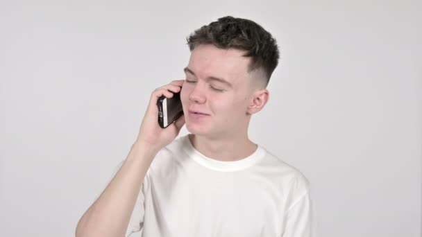 Молодой человек говорит по смартфону на белом фоне — стоковое видео