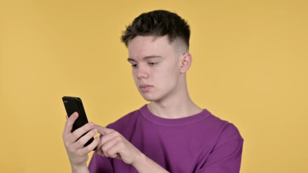 Young Man Browsing Smartphone on Yellow Background — Stock Video