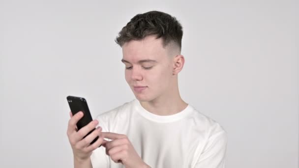 Hombre joven navegando Smartphone sobre fondo blanco — Vídeo de stock