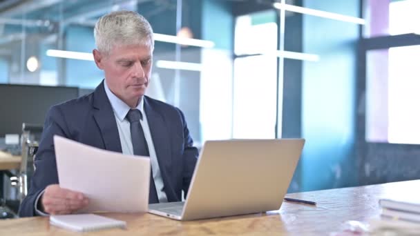 Middle Aged Businessman reading Document and using Laptop — Stock Video