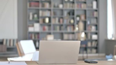 Ciddi Orta yaşlı adam geri geliyor ve dizüstü bilgisayarla masada oturuyor