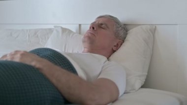Orta yaşlı adam tek başına yatakta uyumaya çalışıyor.