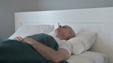 Orta yaşlı adam kâbus gördükten sonra yatakta uyanıyor.